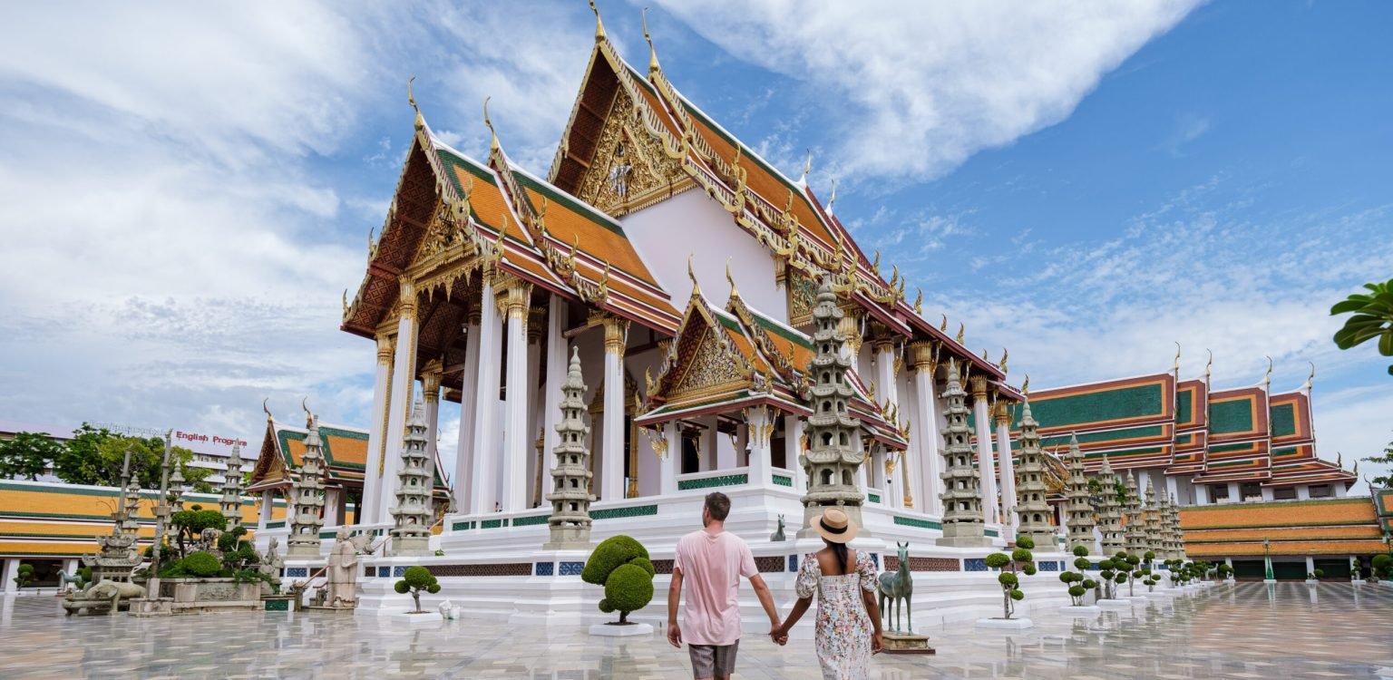 Bangkok Thailand, Wat Suthat Thepwararam Ratchaworahawihan temple in old city of Bangkok Bangkok Thailand, Wat Suthat Thepwararam Ratchaworahawihan temple in the old city of Bangkok. Asian woman and European men walking by a temple in Bangkok on a hot day in the city