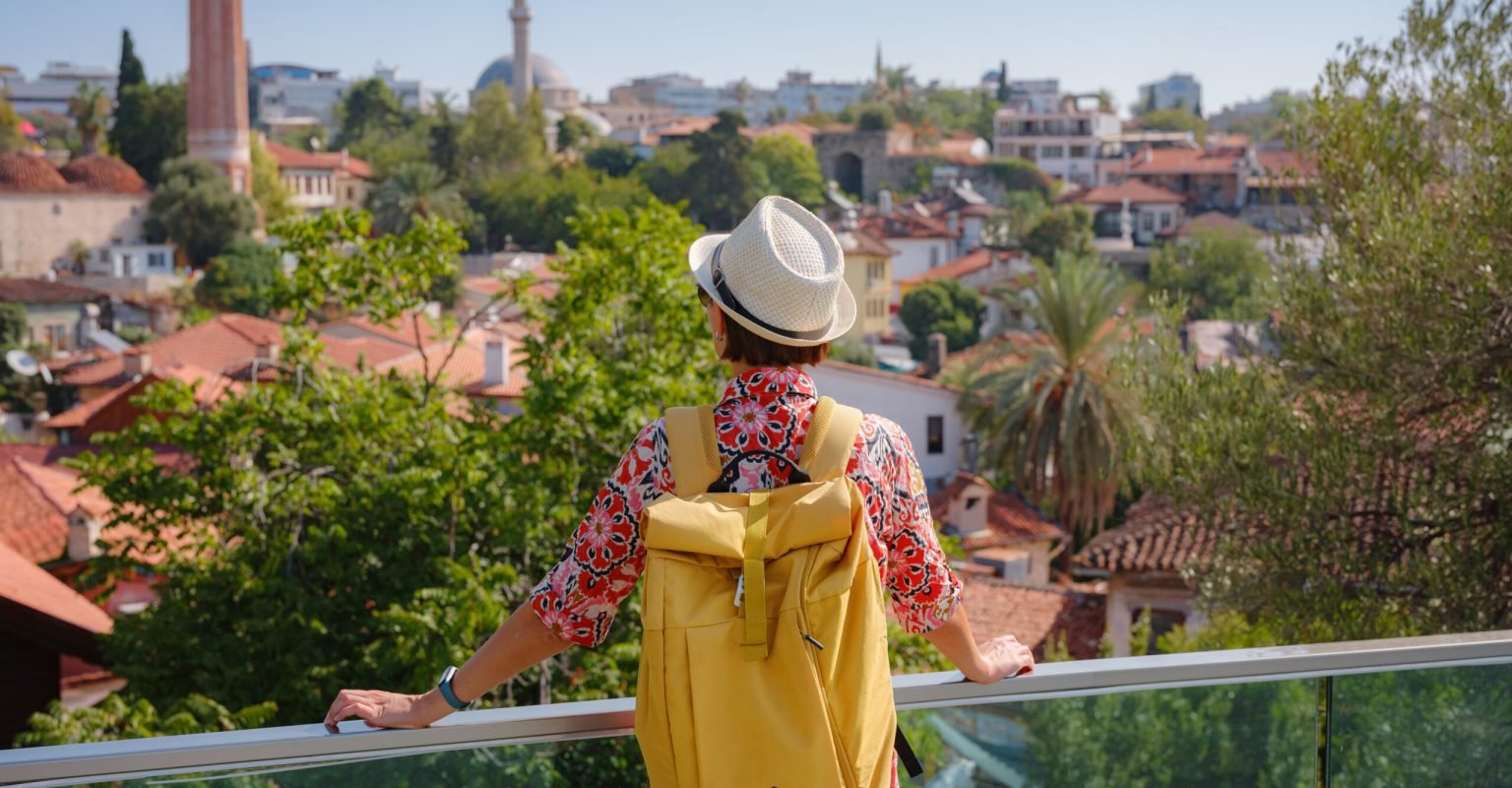female summer travel to Antalya, Turkey female summer travel to Antalya, Turkey. young asian woman in red dress walk through old town Kalechi , Panoramic view of Antalya Old Town port, Taurus mountains and Mediterrranean Sea, Turkey