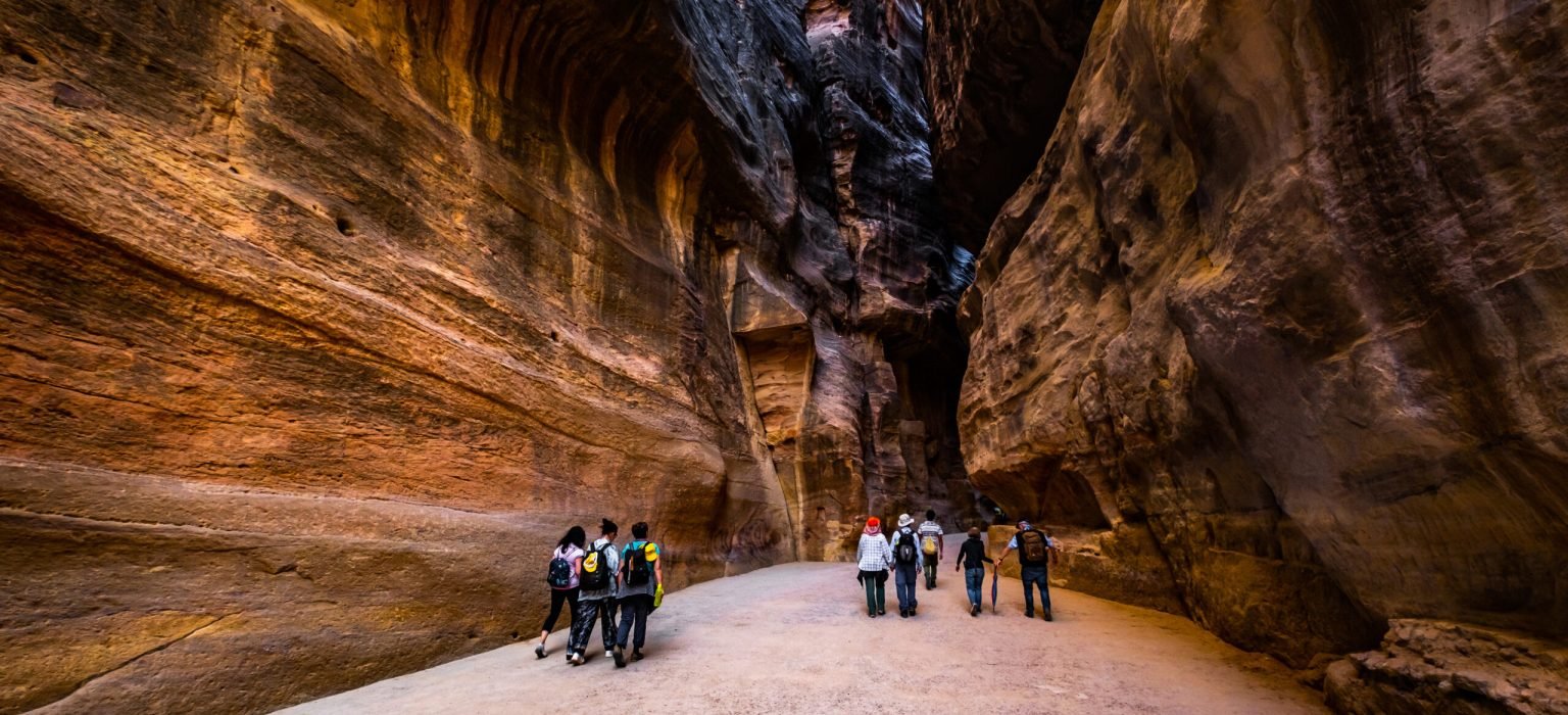 Group of tourists between rocks, Jordan Group of people between sandstone rocks at narrow path in Petra, Jordan