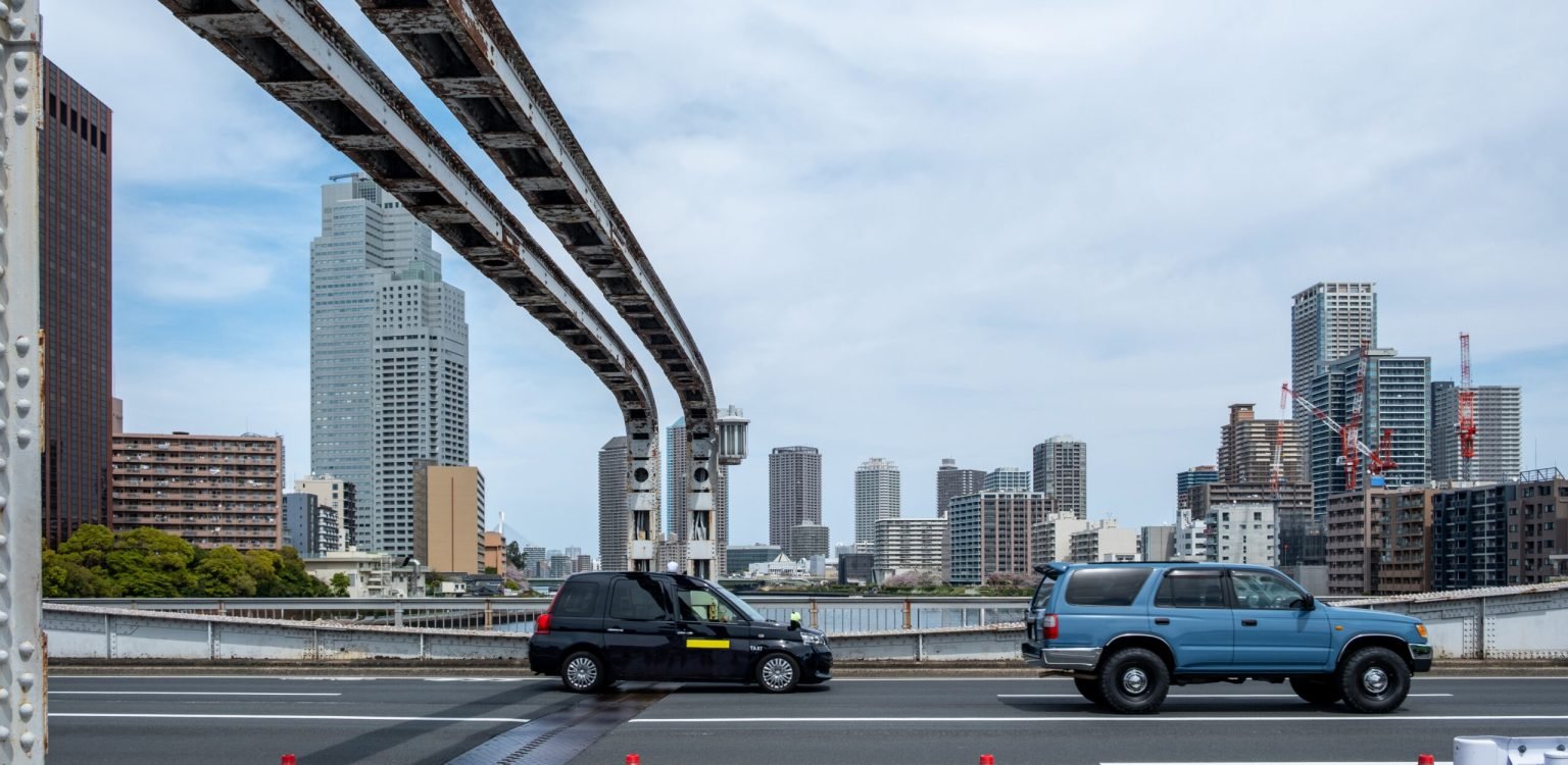 Tokyo city Japan. Cars on bridge over river canal, Modern high rise apartment and office buildings background