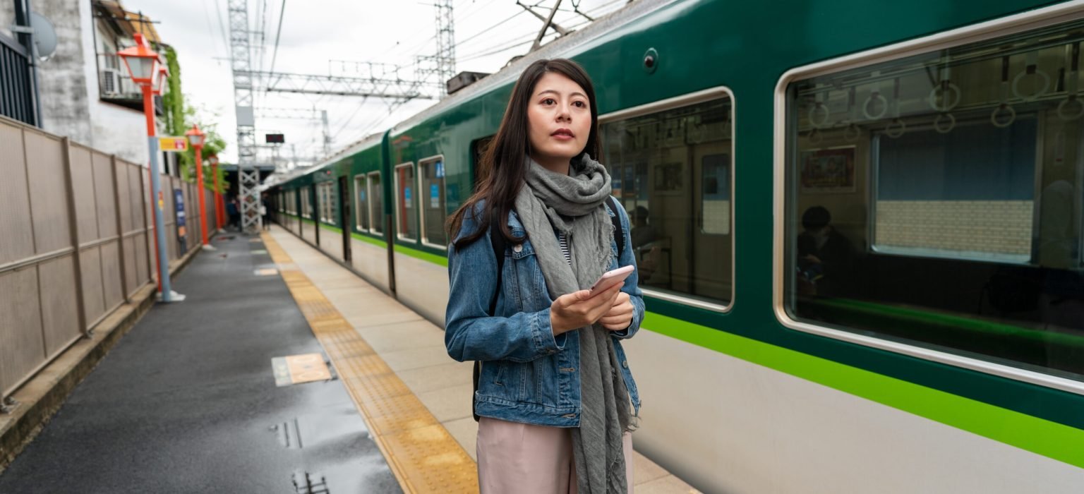 woman standing on platform at inari station confused asian Japanese woman tourist standing on the platform and looking into distance, not sure which way to go after getting off green train at inari station in Kyoto japan